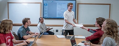 a person passing out papers in a small classroom