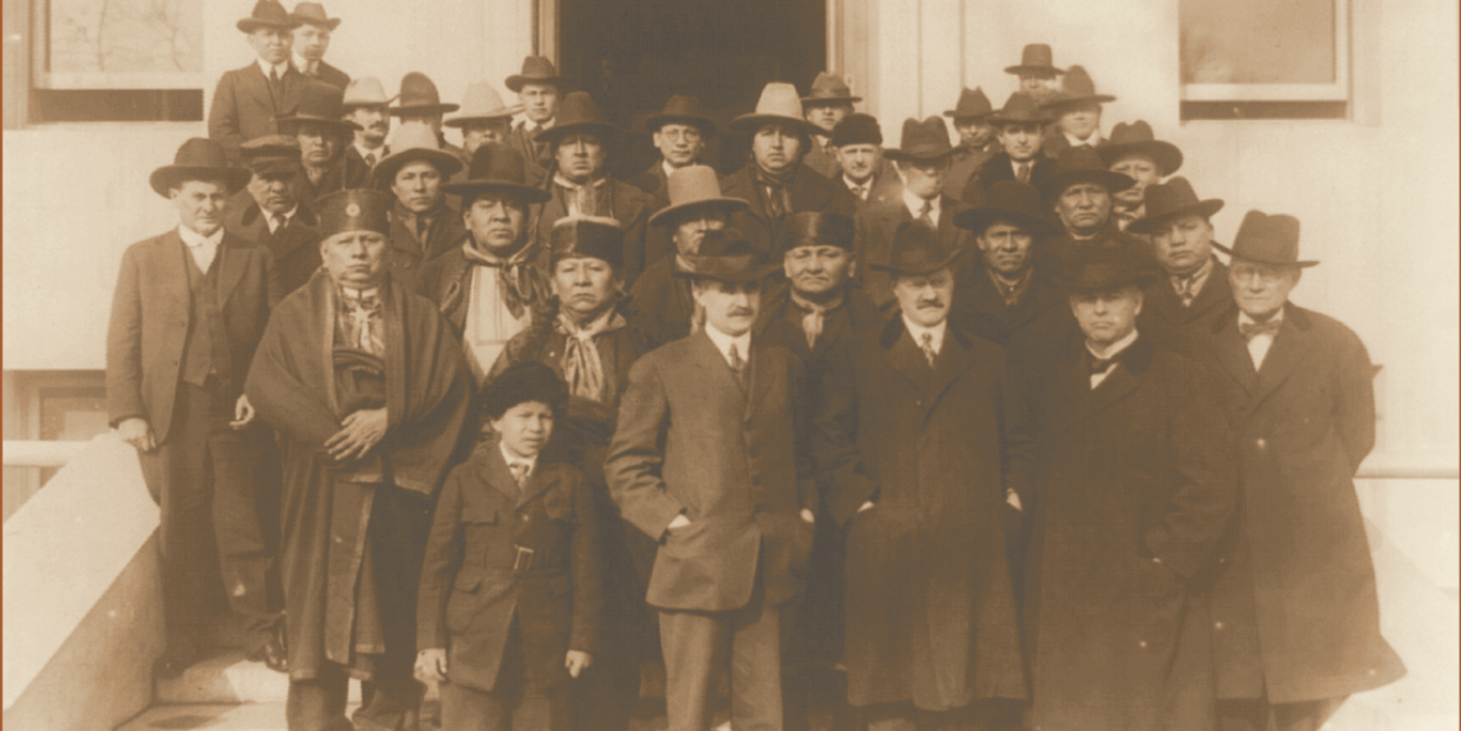 old sepia tone image of men standing on stairs with coats and hats on