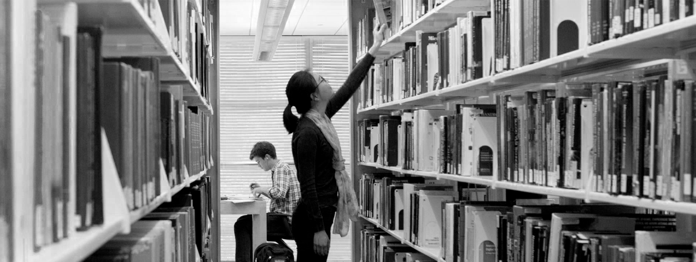 Woman pulling book from the shelf in the library