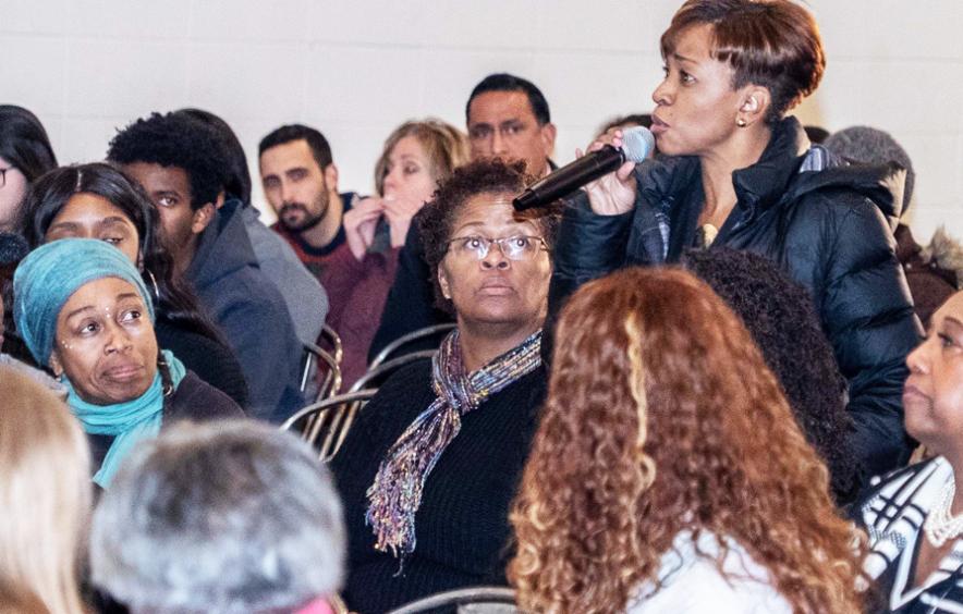 Black woman speaking in mic at townhall