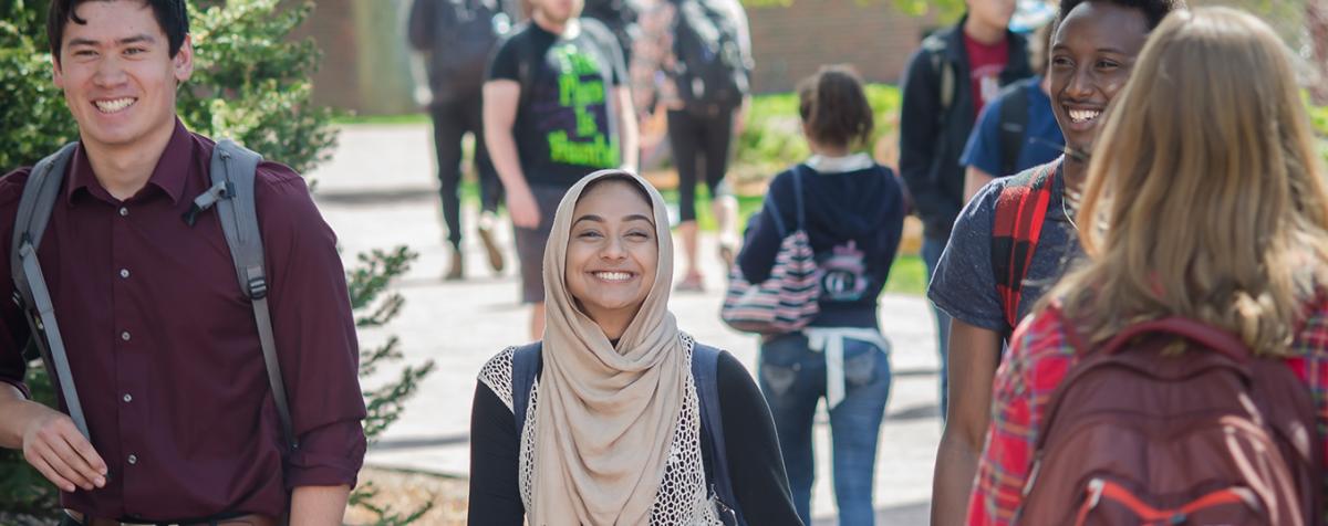 students walking on campus. Woman with headscarf smiling